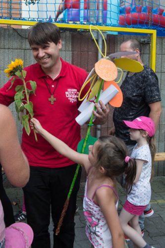 Kind reicht Pater Johannes eine Blume